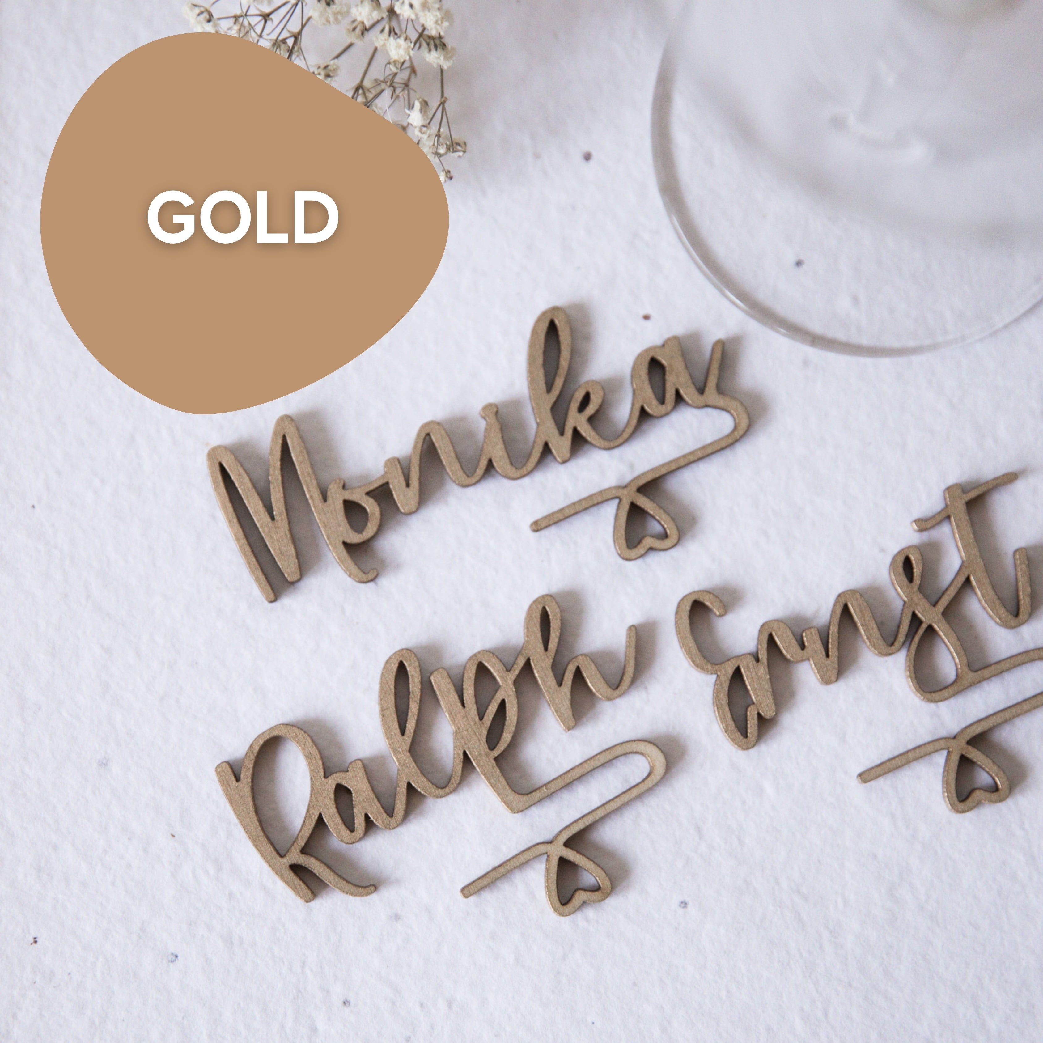 Glasmarkierer mit Namen von Laserhelden – stilvolle, personalisierte Namensschilder wie „Monika“ und „Ralph Ernst“ als elegante Glasmarkierer auf weißer Struktur, perfekt für Events.