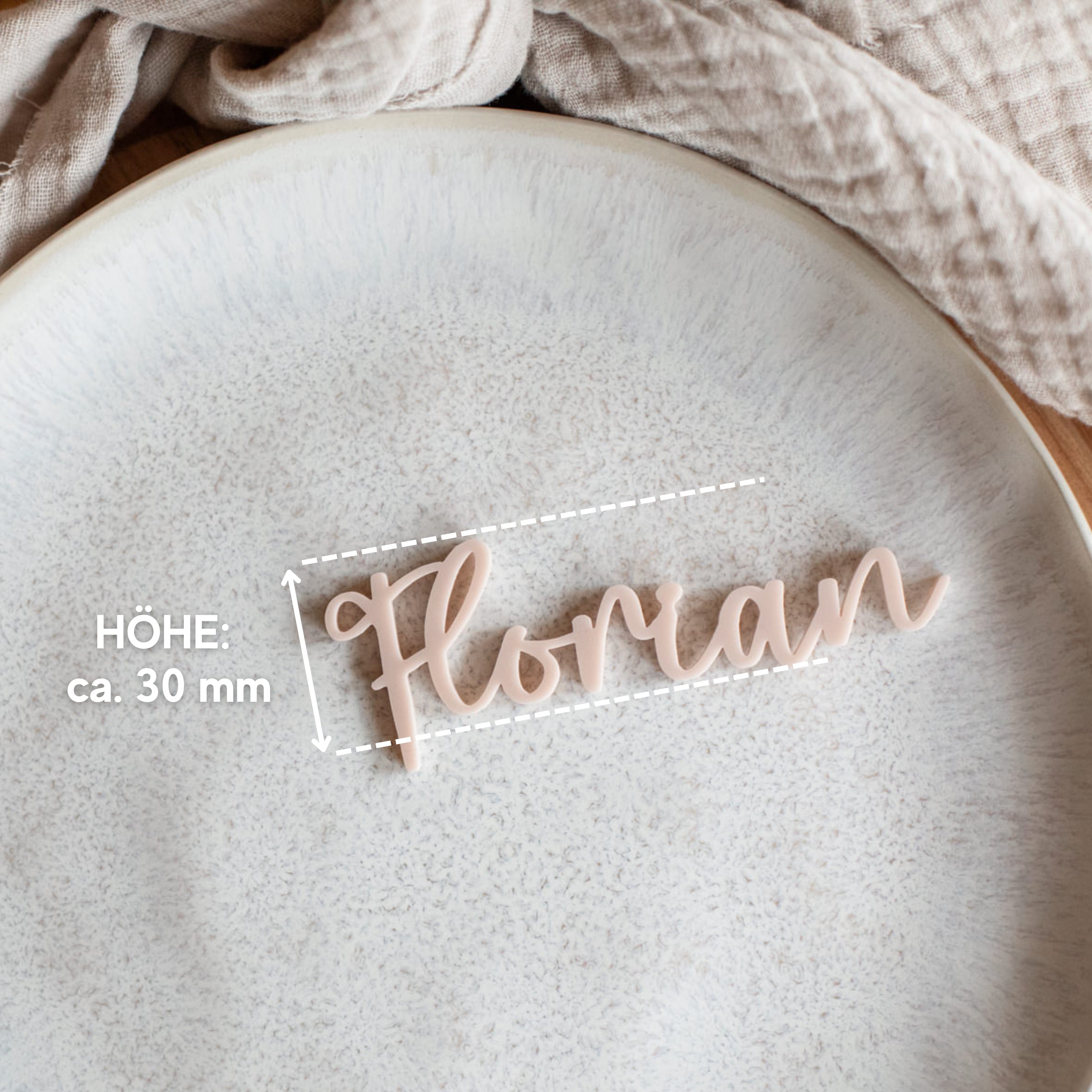 Geschwungener beiger Text „floran“ auf Strukturplatte mit Stoffhintergrund, edel verarbeitet als personalisiertes Namensschild Hochzeit von Laserhelden, Größe 30 mm.