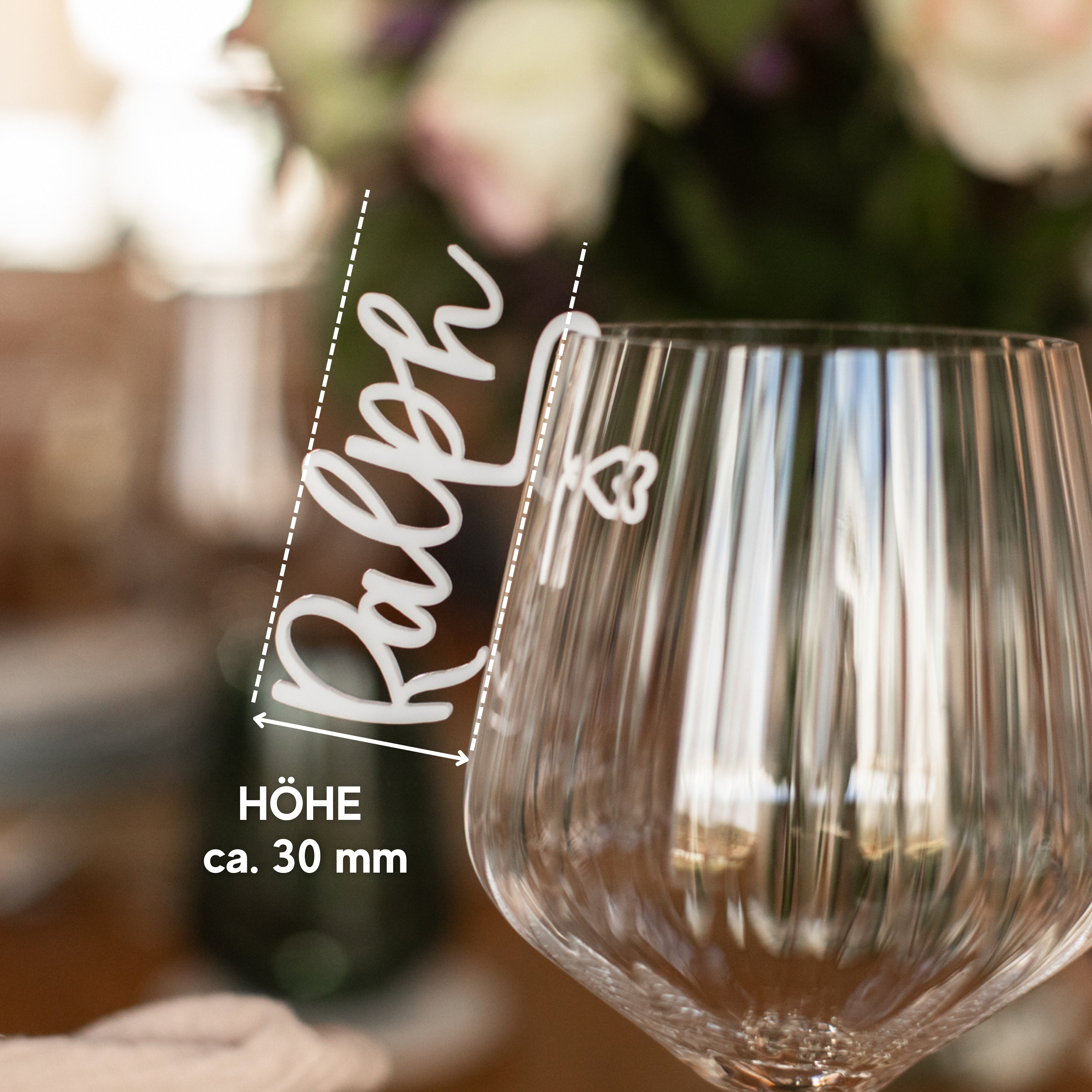 Nahaufnahme eines Weinglases mit der eleganten Gravur „Ralph“ von Laserhelden, mit einem Pfeil, der auf die 30 mm hohe Schrift zeigt – ideal für alle, die nach einzigartigen „Namensschildern für Hochzeiten“ oder einem personalisierten Glasmarkierer aus Acryl suchen.