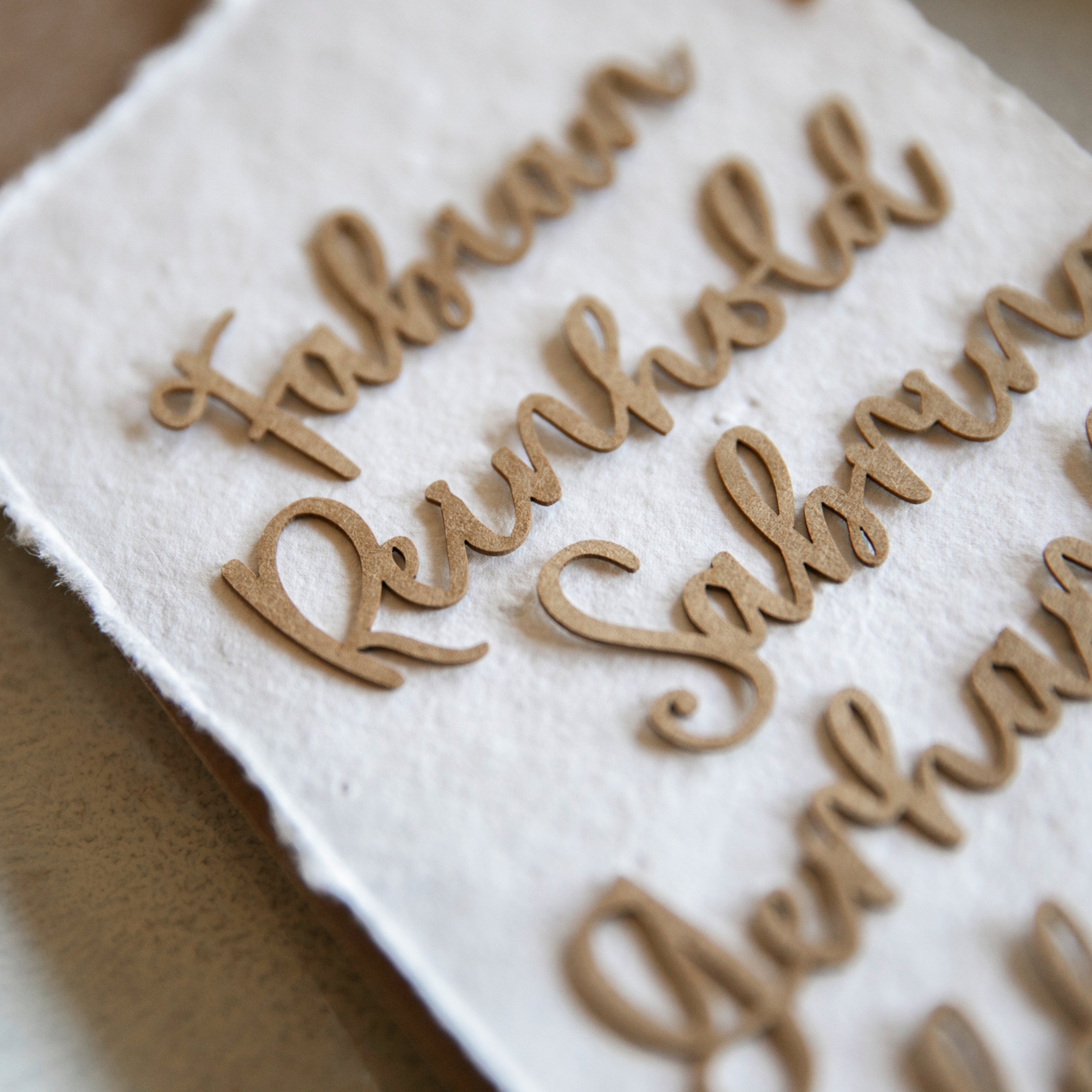 Das Namensschild Hochzeit von Laserhelden zeigt kursive Holznamen auf Kraftpapier wie „Fabian“ und „Reinhold“, ideal für personalisierte Namensschilder bei einer Boho-Hochzeit.