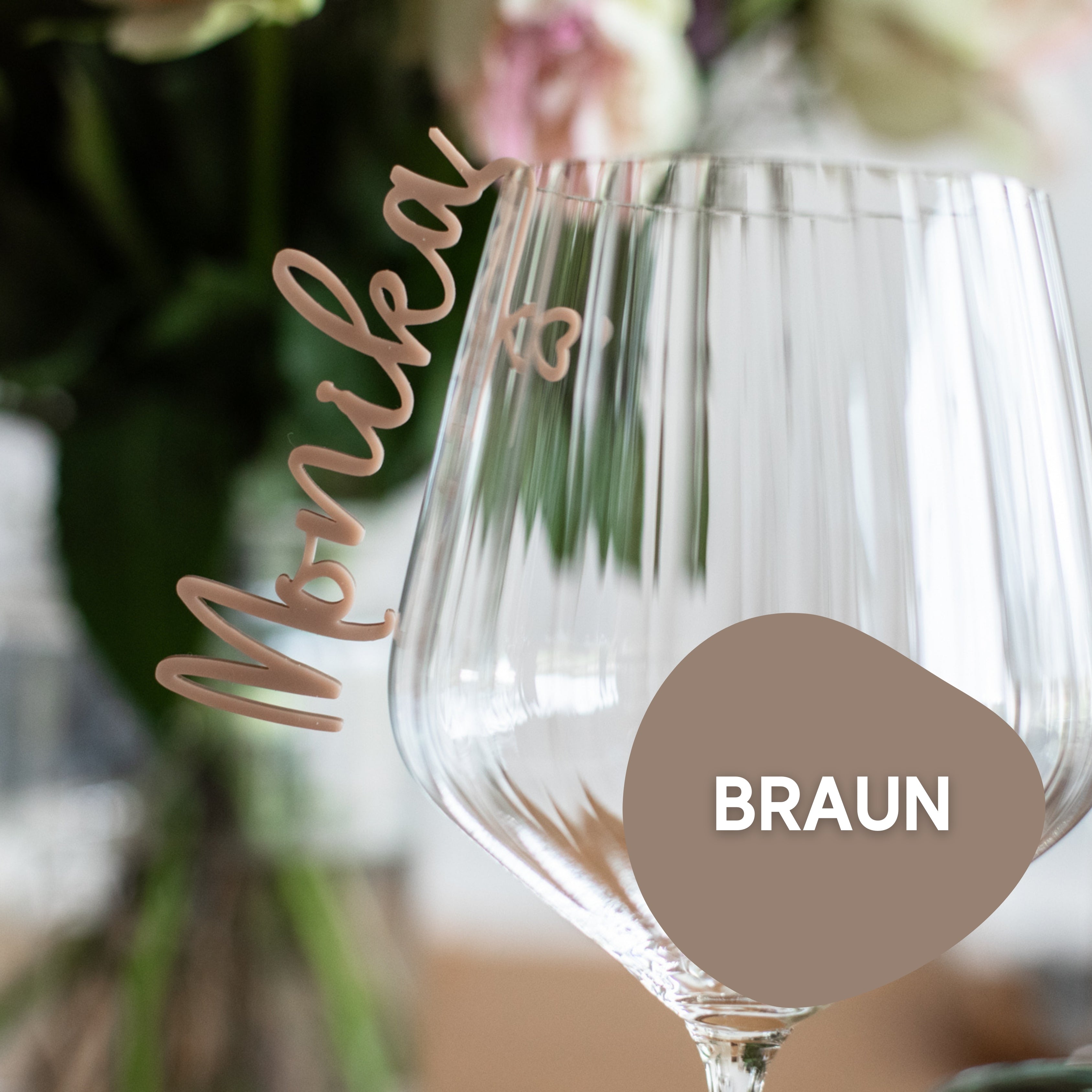 Ein personalisierter Acrylglasmarker von Laserhelden zeigt den Namen „Monika“ auf einem floralen Hintergrund mit einer braunen Form mit der Aufschrift „BRAUN“ und bietet eine elegante Note ähnlich einer Tischkarte aus Acryl.