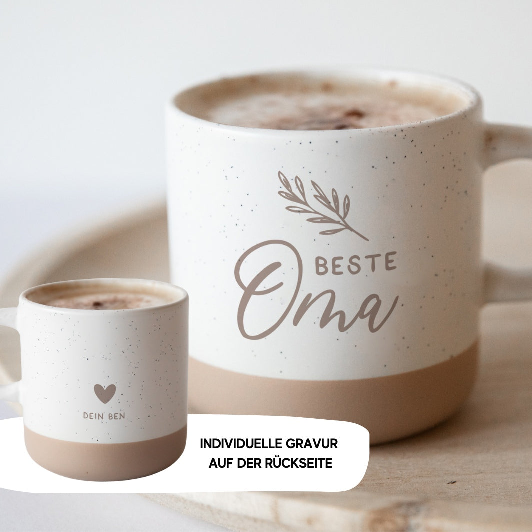 Die personalisierte Tasse aus Steingut von laserhelden ist beige, trägt vorn „Beste Oma“ mit Blatt und hat eine Gravur mit Herz auf der Rückseite – das perfekte Geschenk für besondere Anlässe.